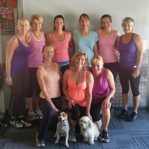 Nine women attending the Shedfit Personal Training Studio smiling for group photo including two small dogs